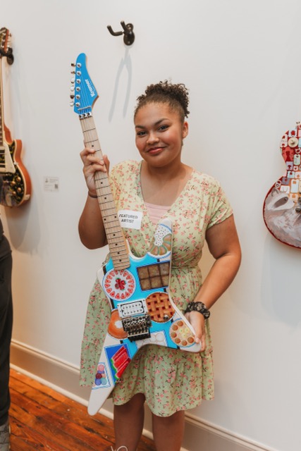 Dogwood Arts Youth Arts Program Artist Holds the Guitar She Painted in 2025